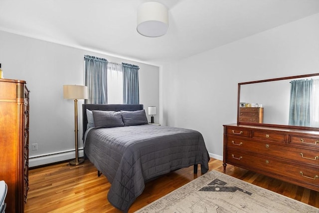 bedroom featuring baseboards, baseboard heating, and wood finished floors