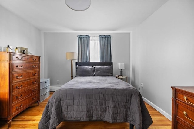 bedroom featuring baseboard heating, baseboards, and light wood-style flooring