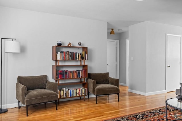 sitting room with baseboards and light wood-style flooring