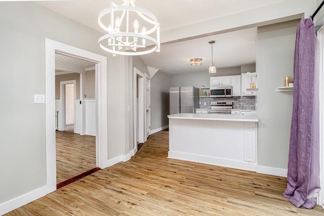 353 Front St, Winchendon, MA 01475 - kitchen featuring stainless steel appliances, a peninsula, light wood-style floors, a chandelier, and tasteful backsplash