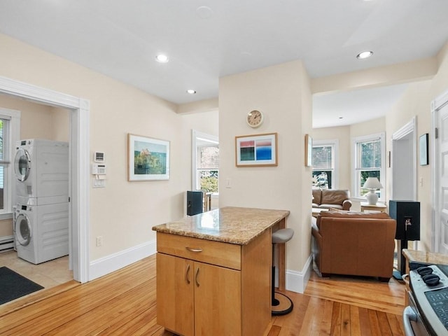 110 Woerd Ave, Waltham, MA 02453 - kitchen featuring stacked washer and clothes dryer, light wood-style flooring, a center island, recessed lighting, and open floor plan