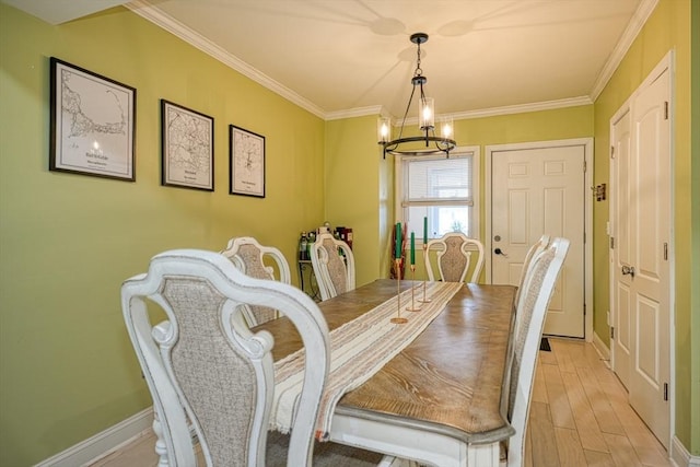 dining space with crown molding, light wood-type flooring, and an inviting chandelier