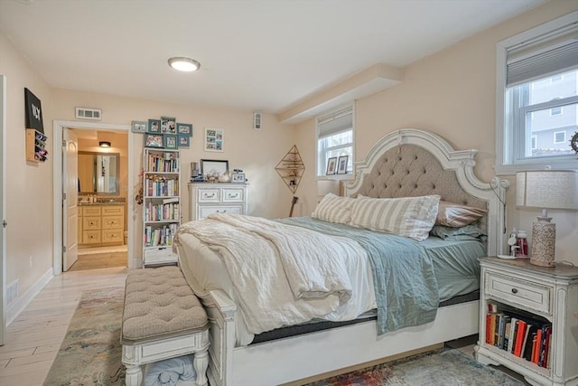 bedroom with light wood-type flooring and ensuite bath