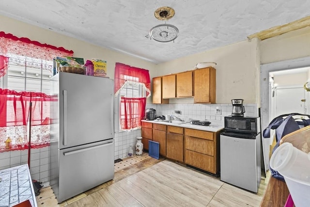 kitchen with a healthy amount of sunlight, light hardwood / wood-style flooring, and stainless steel fridge