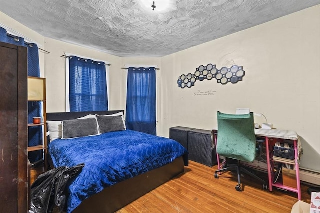 bedroom with a textured ceiling and wood-type flooring