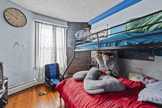 bedroom with a baseboard radiator and hardwood / wood-style flooring