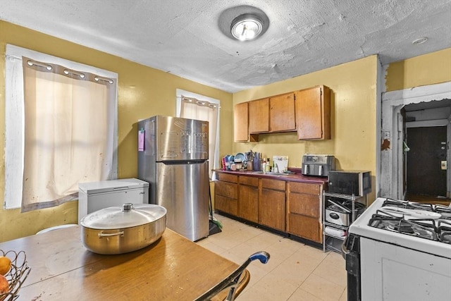 kitchen featuring sink, a textured ceiling, stainless steel fridge, and white gas stove