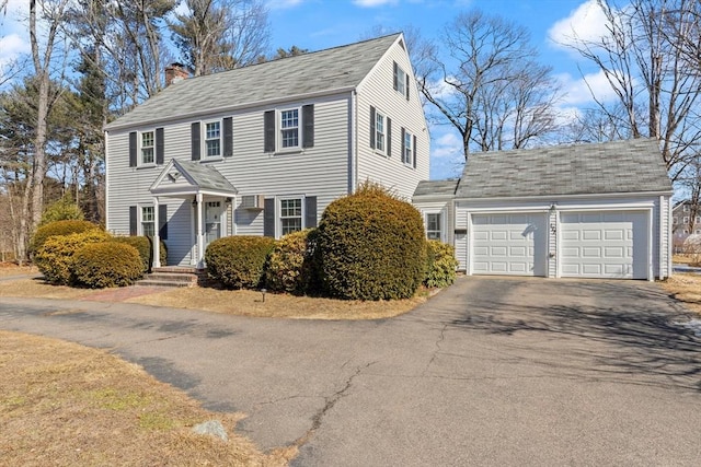 colonial house with a garage, driveway, and a chimney