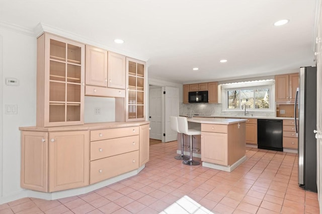 kitchen featuring a kitchen breakfast bar, black appliances, light brown cabinets, and light countertops