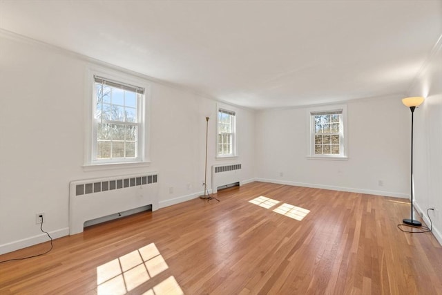 unfurnished room featuring light wood-style flooring, radiator, baseboards, and ornamental molding