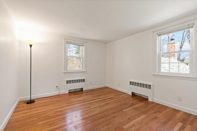 unfurnished room featuring light wood-style floors, radiator, and a healthy amount of sunlight