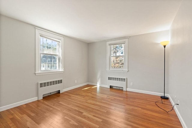 spare room with radiator, light wood-style floors, and plenty of natural light