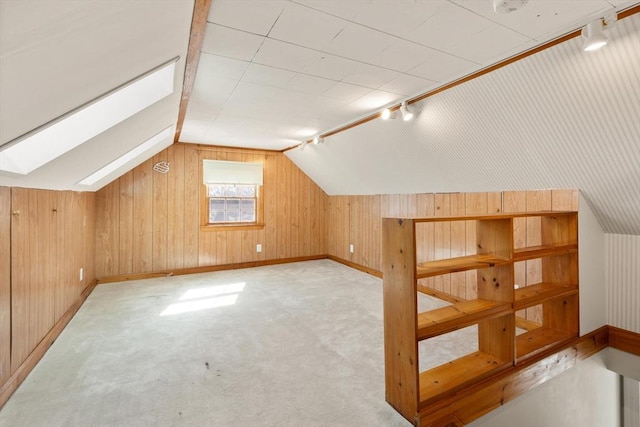 additional living space featuring baseboards, lofted ceiling with skylight, carpet floors, and wood walls