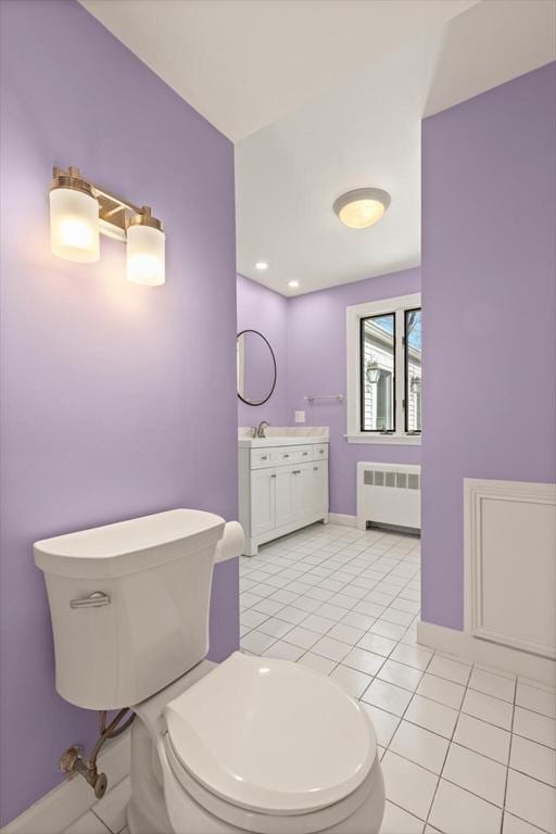 bathroom with tile patterned floors, toilet, radiator heating unit, baseboards, and vanity