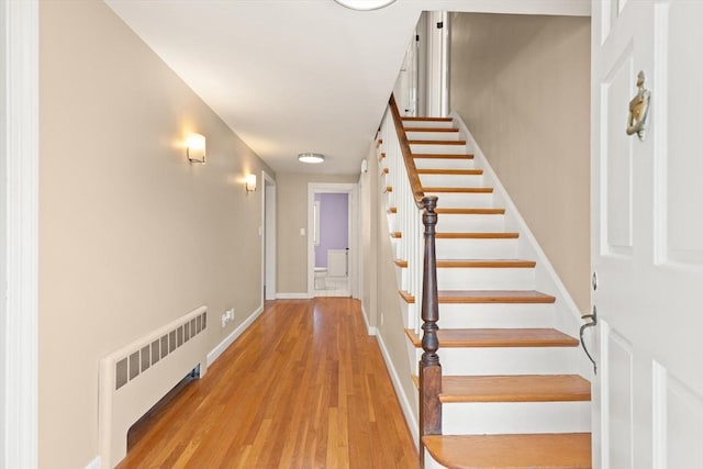 stairs with radiator, baseboards, and wood finished floors