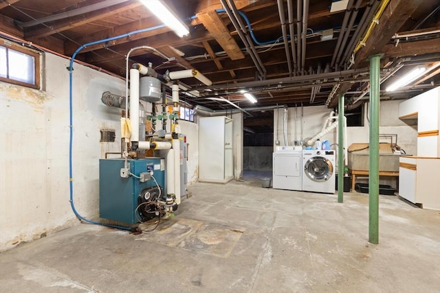 basement with washing machine and dryer, a heating unit, and electric water heater