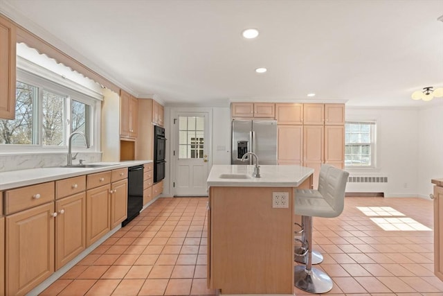 kitchen featuring a sink, radiator, black appliances, and light tile patterned flooring