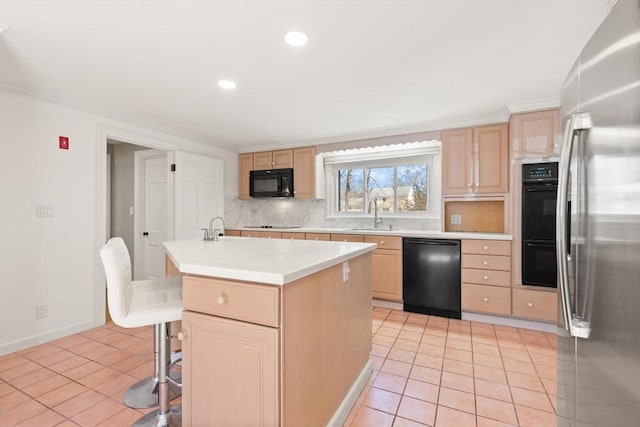 kitchen with backsplash, light brown cabinets, black appliances, and light countertops