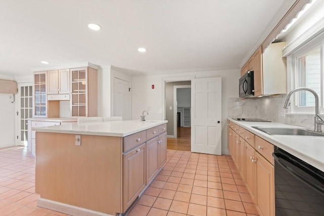 kitchen with black appliances, tasteful backsplash, a center island with sink, and a sink