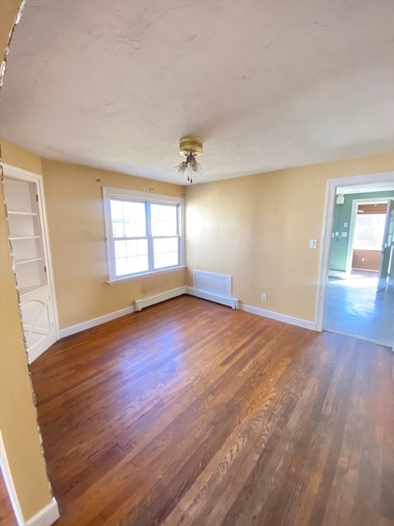 unfurnished room featuring ceiling fan, baseboard heating, and dark wood-type flooring