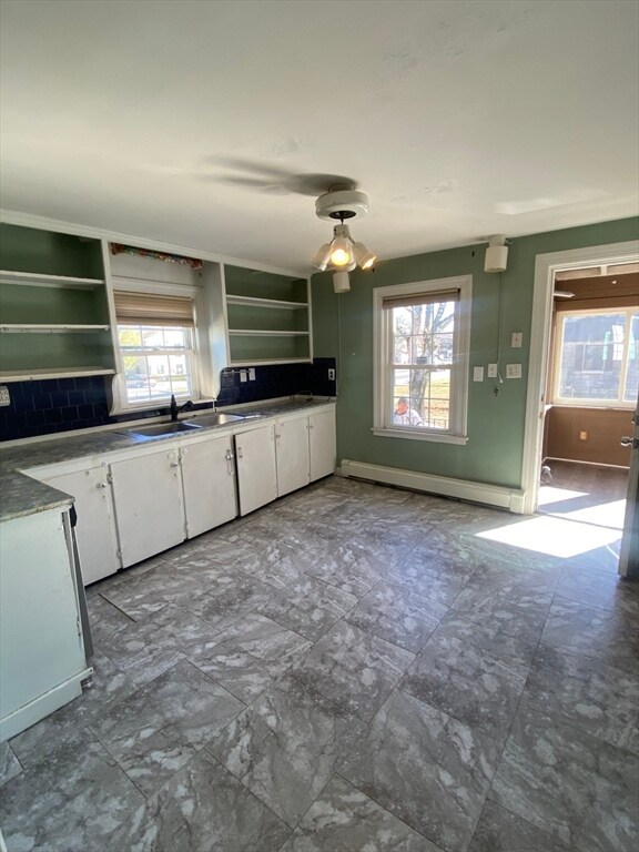 kitchen featuring baseboard heating, a wealth of natural light, white cabinetry, and sink