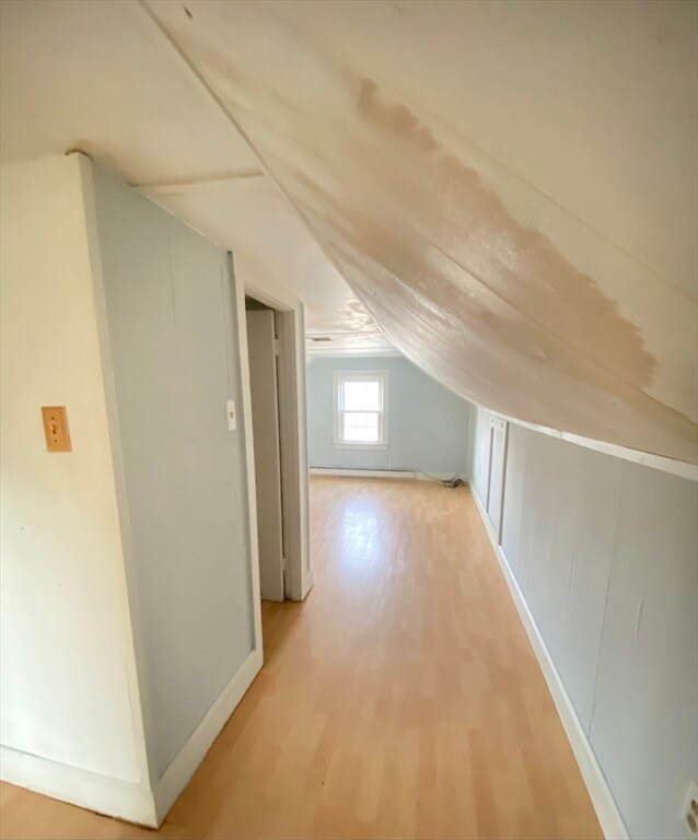 bonus room with wood-type flooring and vaulted ceiling