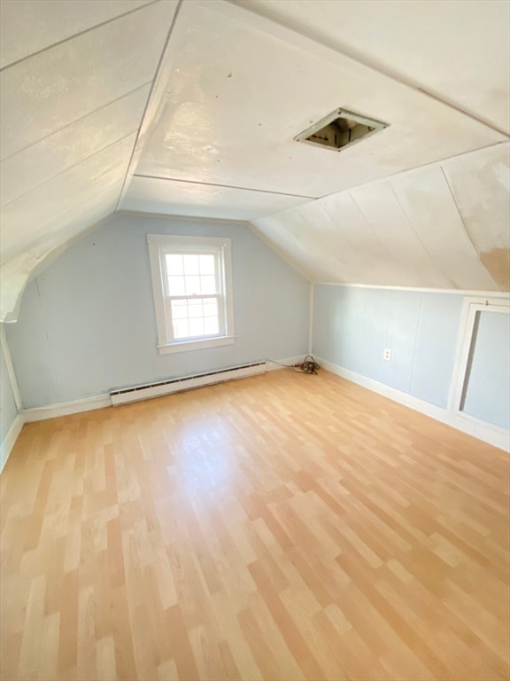 additional living space featuring a baseboard radiator, vaulted ceiling, and light wood-type flooring