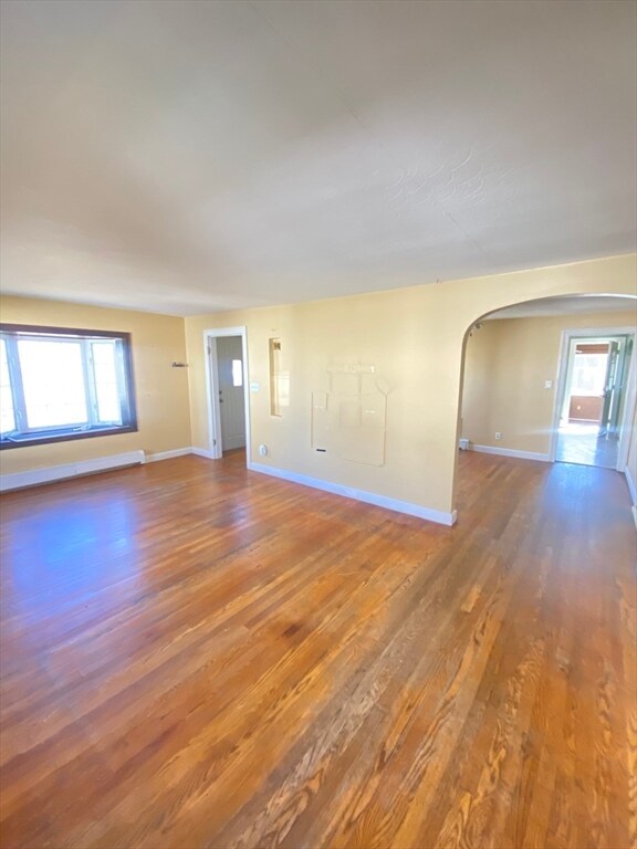 unfurnished room with dark hardwood / wood-style floors and baseboard heating