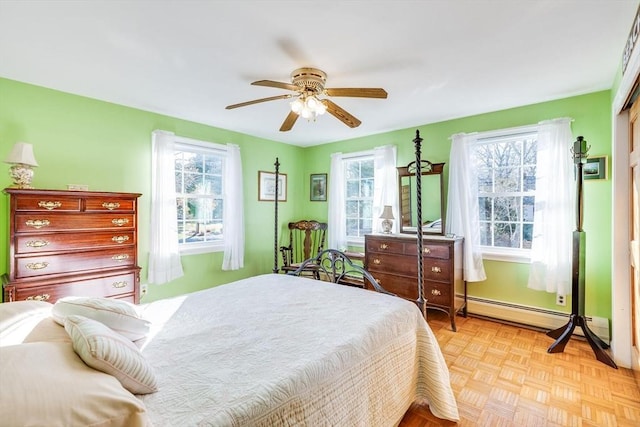 bedroom with light parquet floors, multiple windows, a baseboard heating unit, and ceiling fan