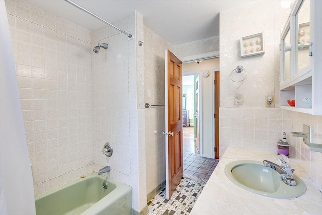 bathroom featuring tile patterned floors, vanity, tiled shower / bath combo, and tile walls