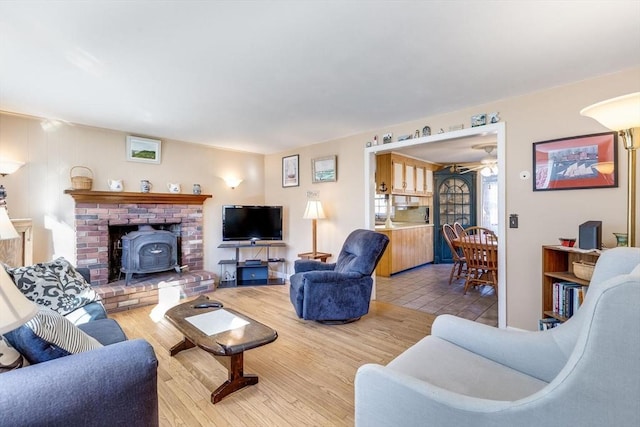 living room featuring light hardwood / wood-style flooring, a wood stove, and ceiling fan