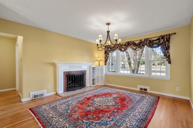 living room featuring hardwood / wood-style floors, a notable chandelier, and a fireplace