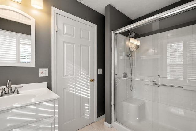 bathroom with tile patterned flooring, a shower with door, and sink