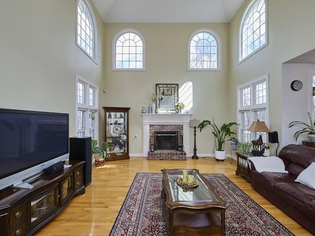 living area featuring a brick fireplace, baseboards, and light wood-type flooring