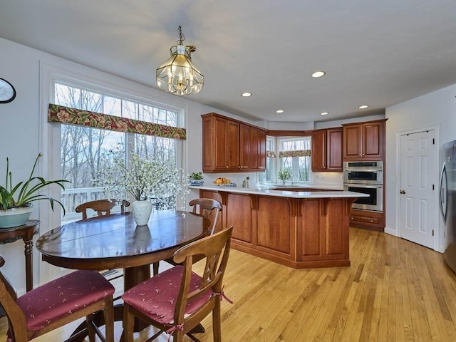 kitchen featuring light wood-type flooring, light countertops, recessed lighting, a peninsula, and stainless steel appliances