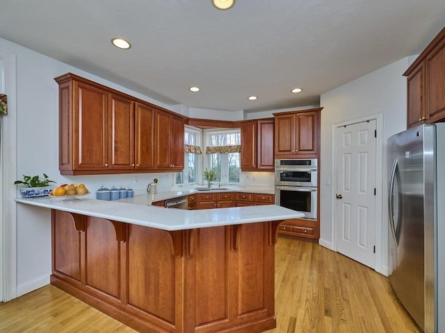 kitchen featuring a kitchen breakfast bar, light wood-style flooring, appliances with stainless steel finishes, and a peninsula