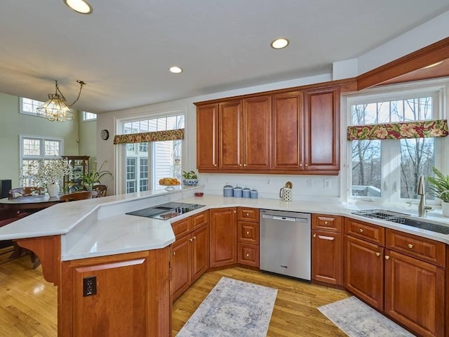 kitchen featuring light countertops, a kitchen bar, a peninsula, stainless steel dishwasher, and a sink