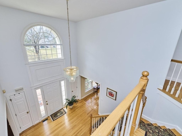 entrance foyer featuring baseboards, a high ceiling, and light wood-style flooring