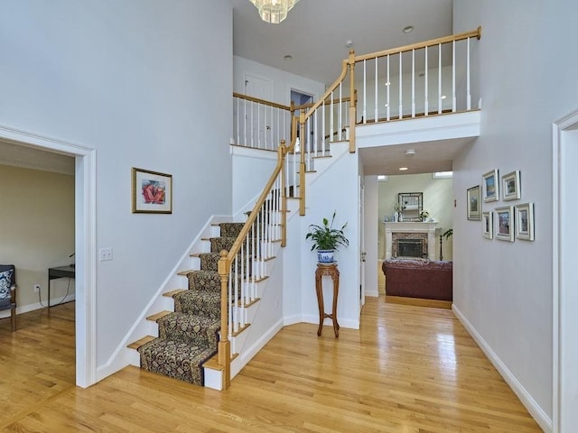 stairway with baseboards, a high ceiling, wood finished floors, and a fireplace