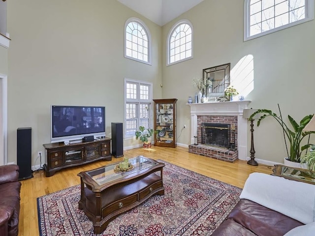 living room with a brick fireplace, wood finished floors, and baseboards