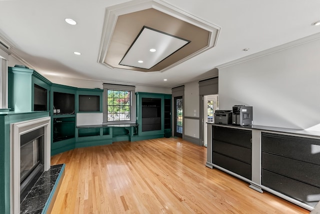 kitchen featuring a premium fireplace, crown molding, green cabinets, and light wood-type flooring