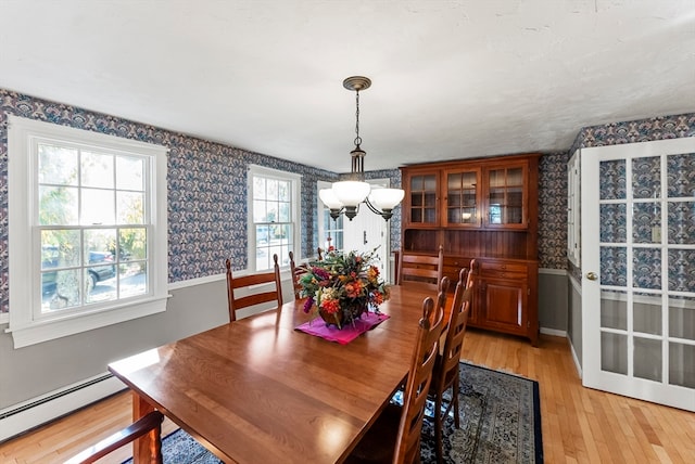 dining area featuring baseboard heating, a chandelier, and light wood-type flooring