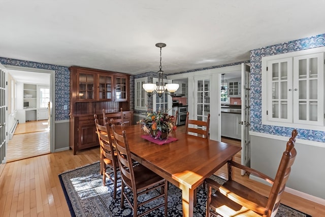 dining room with baseboard heating, an inviting chandelier, and light wood-type flooring