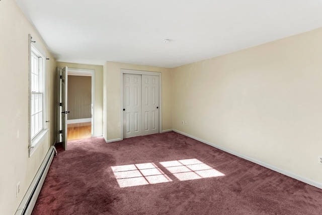 unfurnished bedroom featuring baseboard heating, dark carpet, and a closet