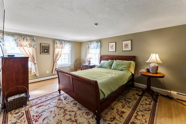 bedroom with light hardwood / wood-style floors, a baseboard heating unit, and ornamental molding