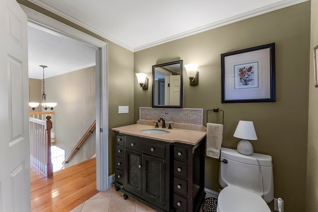 bathroom with toilet, tile patterned flooring, backsplash, crown molding, and vanity