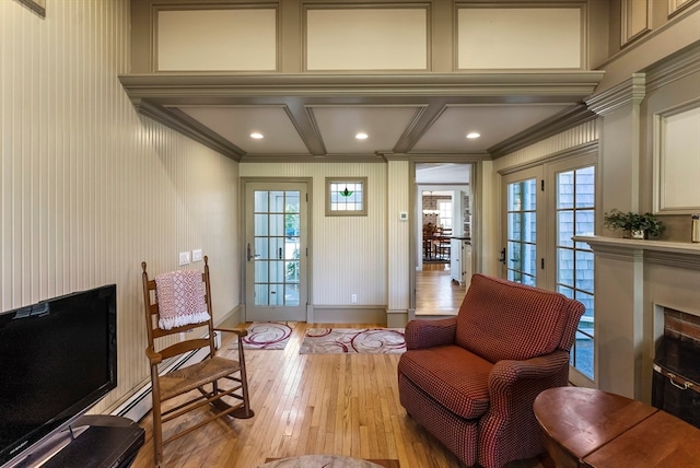 living area featuring coffered ceiling, crown molding, a healthy amount of sunlight, and light hardwood / wood-style flooring