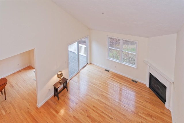 unfurnished living room featuring lofted ceiling and light wood-type flooring