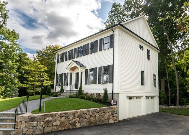 colonial-style house featuring a front lawn, a garage, and driveway