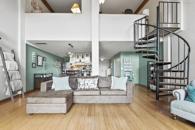 living area with wood finished floors, baseboards, a high ceiling, and stairs